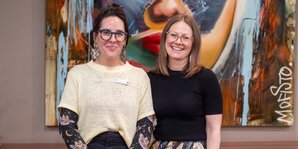 Midwives from the Women's Alcohol and Drug Service pose in front of a painting of a woman.