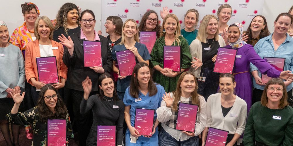 A group of female staff of the Women's holding their scholarships certificates and smiling happily. 