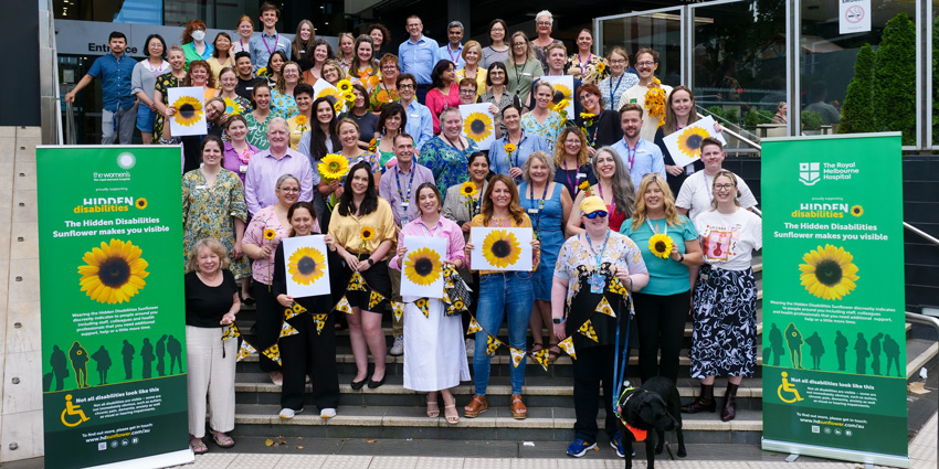 50+ people gathered wearing sunflowers on the steps of the Women's.