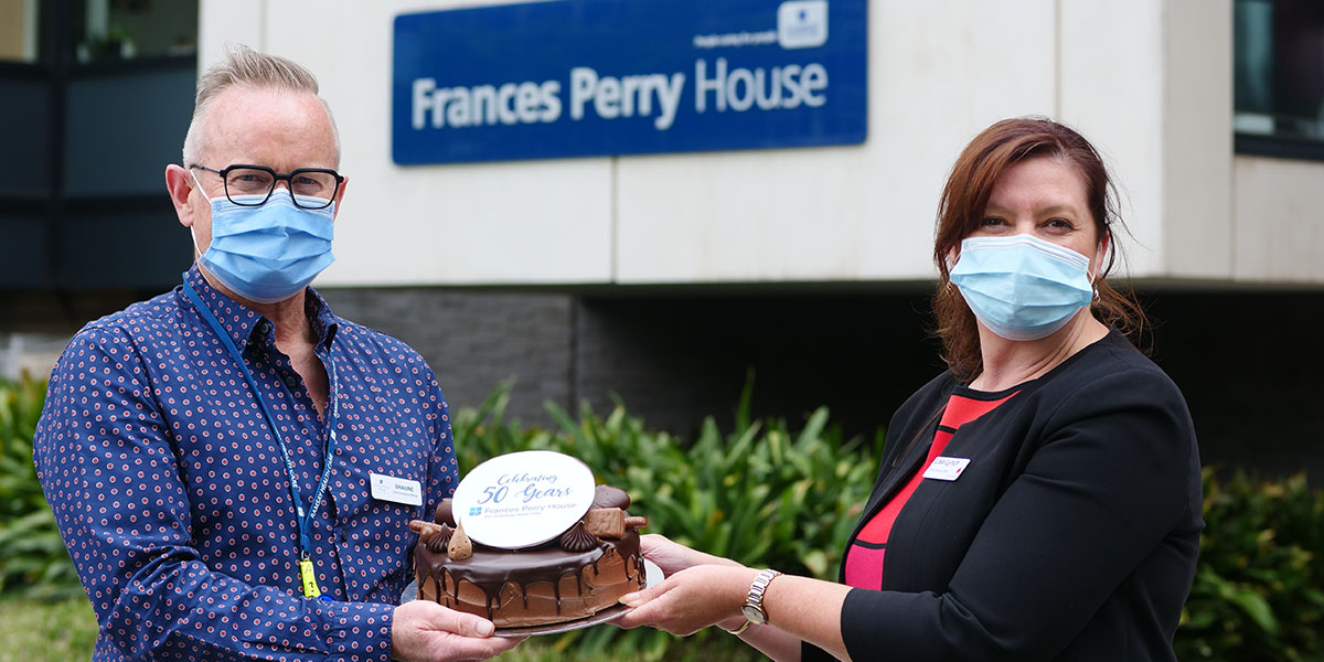 CEO Shaune Gillespie and the Women's COO Lisa Lynch with celebration cake in front of Frances Perry House