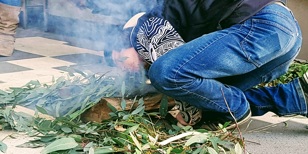Jayden Mills from the Wurundjeri people performs a smoking ceremony at the entrance of the Women's 