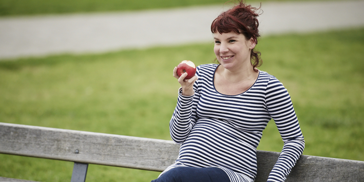 pregnant woman eating an apple