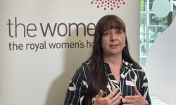 Lisa Lynch chief operations officer standing in front of media banner with news mic in front of her