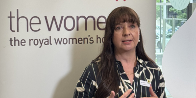 Lisa Lynch chief operations officer standing in front of media banner with news mic in front of her