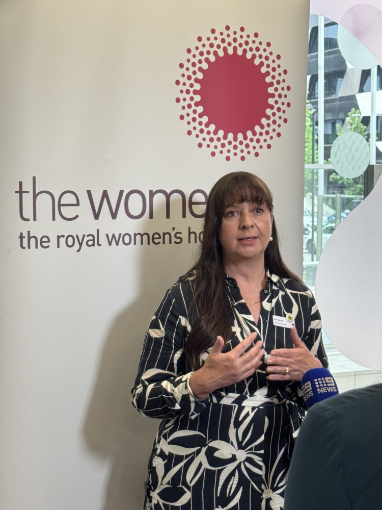 Lisa Lynch chief operations officer standing in front of media banner with news mic in front of her