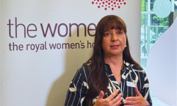 Lisa Lynch chief operations officer standing in front of media banner with news mic in front of her