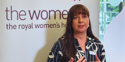 Lisa Lynch chief operations officer standing in front of media banner with news mic in front of her