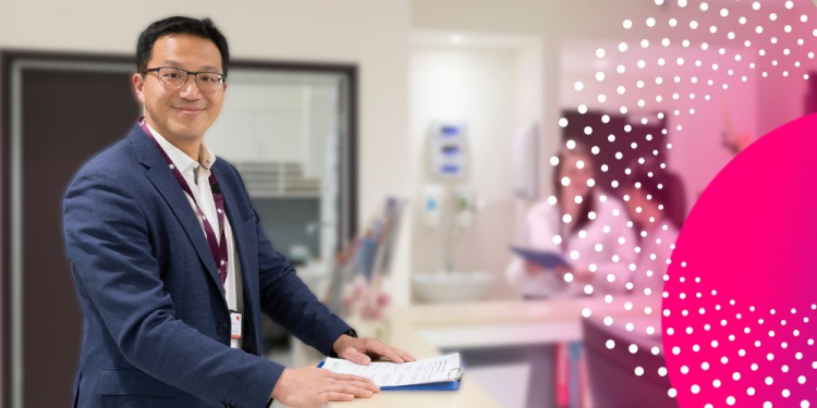 Dr Stephen Lee, Clinical Lead of the Women’s Acute Gynaecology Unit, stands at a counter holding papers.